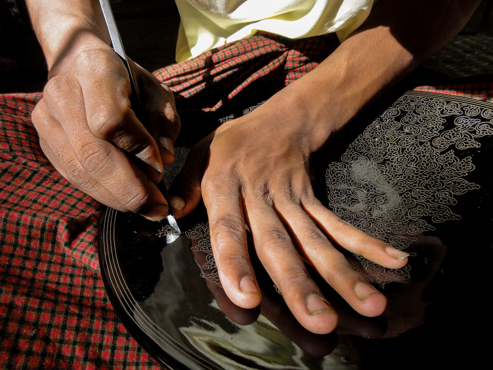 Artists in Bagan working on black lacquer pieces.